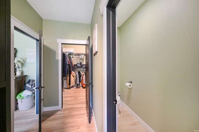 hallway featuring light wood finished floors and baseboards