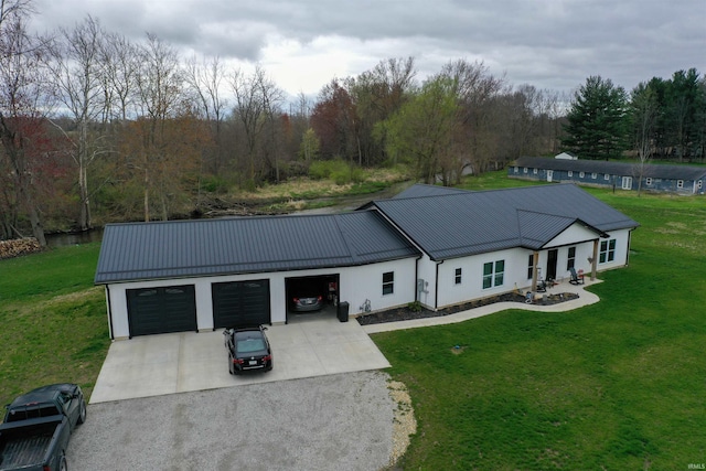 view of front of property featuring a standing seam roof, a front lawn, a garage, metal roof, and concrete driveway