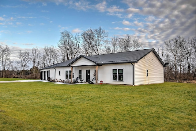 view of front of home featuring driveway, a front yard, metal roof, and a patio area