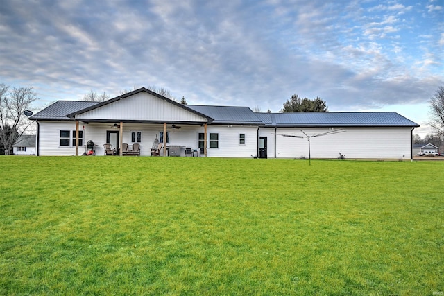 rear view of house featuring a ceiling fan, a yard, and metal roof