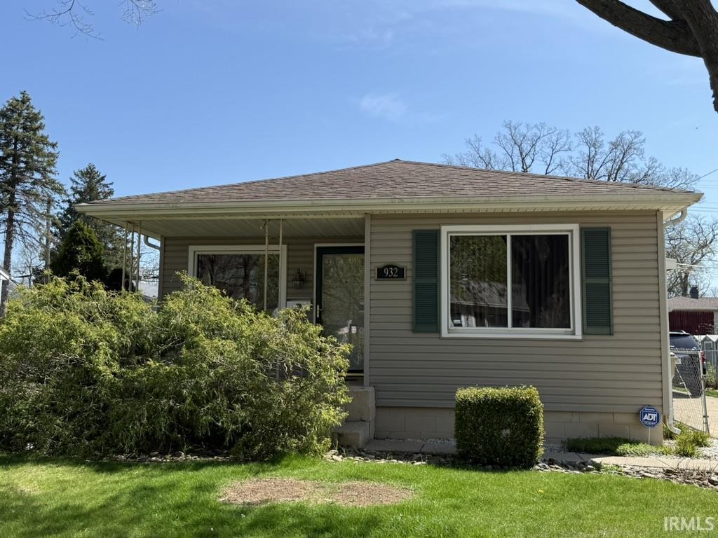 bungalow with a porch, roof with shingles, and a front yard
