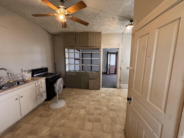 kitchen with white cabinets, a sink, light countertops, black range with gas cooktop, and a ceiling fan