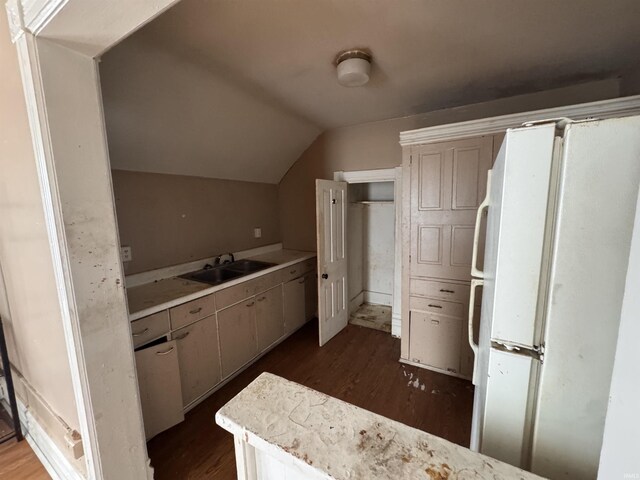 kitchen with dark wood-style floors, vaulted ceiling, a sink, and freestanding refrigerator