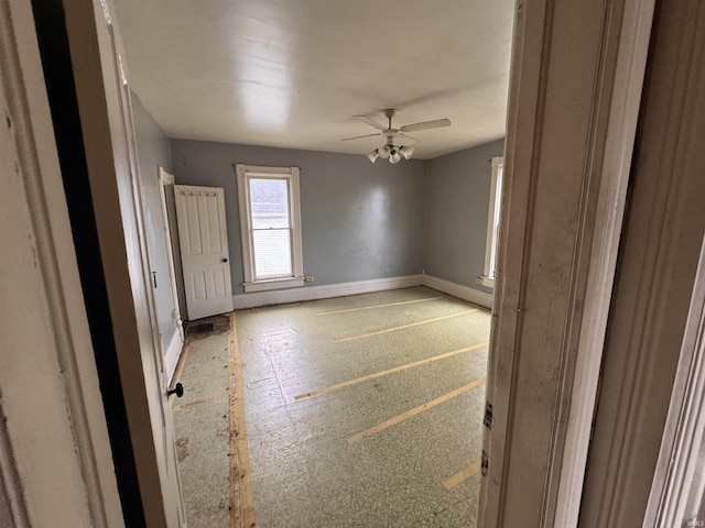 unfurnished room with baseboards and a ceiling fan