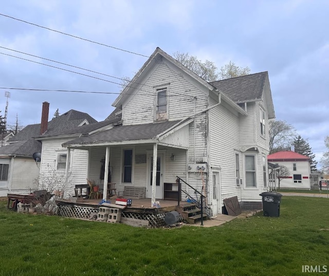 back of house featuring a yard, a porch, and a shingled roof