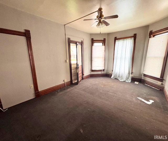 carpeted spare room featuring baseboards and ceiling fan