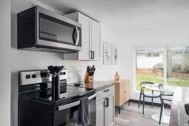 1509 W Glenn Ellyn Dr Unit 9Sfam, Homes Total, Muncie, IN 47304 - kitchen with light wood-style flooring, stainless steel microwave, electric range, white cabinets, and backsplash