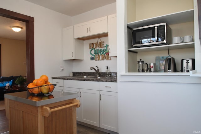 1509 W Glenn Ellyn Dr Unit 9Sfam, Homes Total, Muncie, IN 47304 - kitchen with stainless steel microwave, a sink, white cabinetry, a center island, and dark wood-type flooring