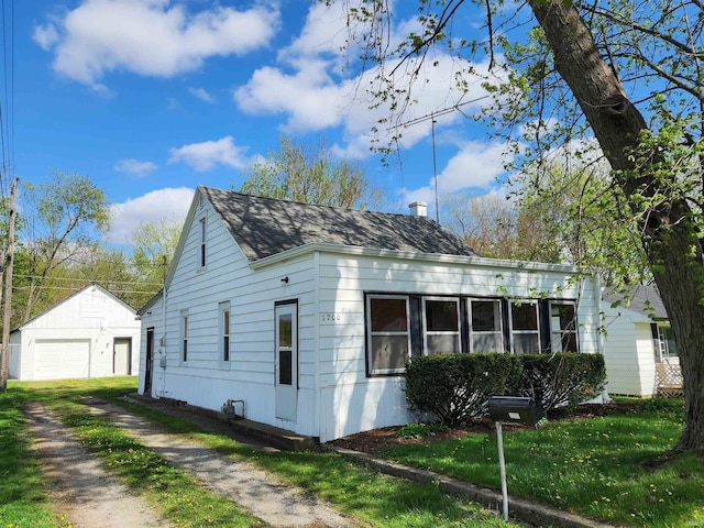 1509 W Glenn Ellyn Dr Unit 9Sfam, Homes Total, Muncie, IN 47304 - view of home's exterior with a detached garage, dirt driveway, an outbuilding, and roof with shingles