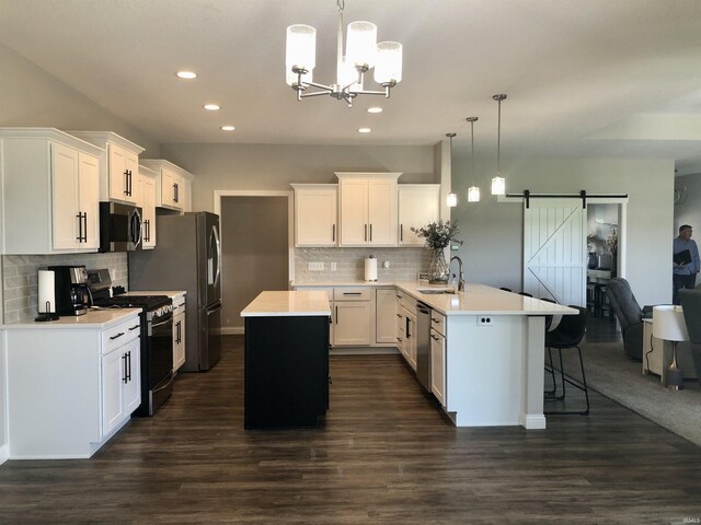 kitchen featuring a barn door, stainless steel appliances, an inviting chandelier, recessed lighting, and a peninsula