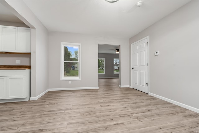unfurnished living room with baseboards, a ceiling fan, and light wood finished floors