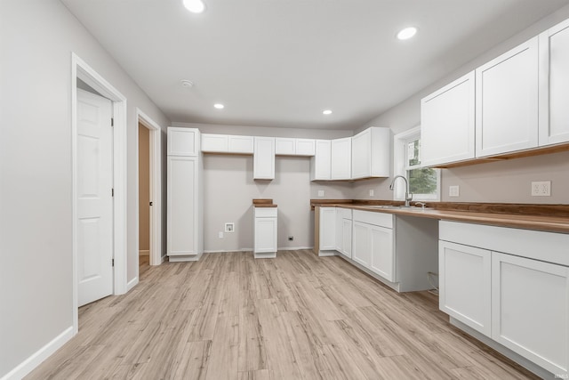 kitchen featuring recessed lighting, a sink, white cabinets, and light wood-style floors