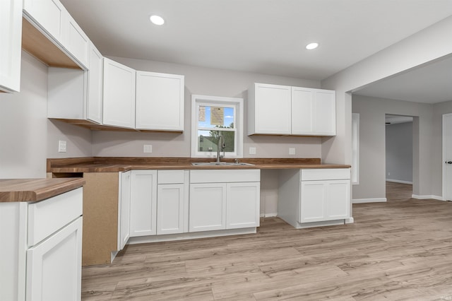 kitchen featuring white cabinetry, light wood-style floors, and a sink