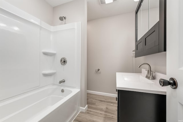 bathroom with baseboards, wood finished floors, bathtub / shower combination, and vanity