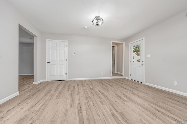 unfurnished living room with baseboards and light wood-type flooring