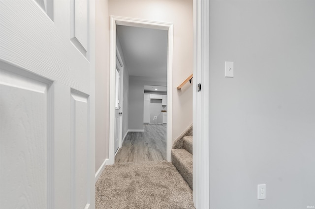 hallway with stairs, carpet flooring, wood finished floors, and baseboards