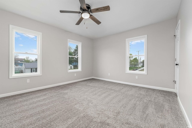 carpeted spare room with ceiling fan and baseboards