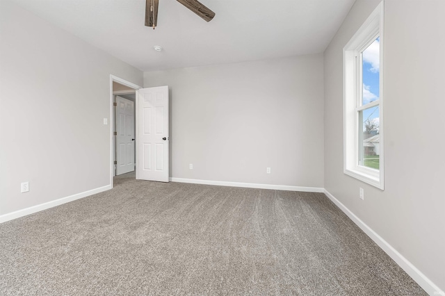 carpeted spare room with ceiling fan and baseboards