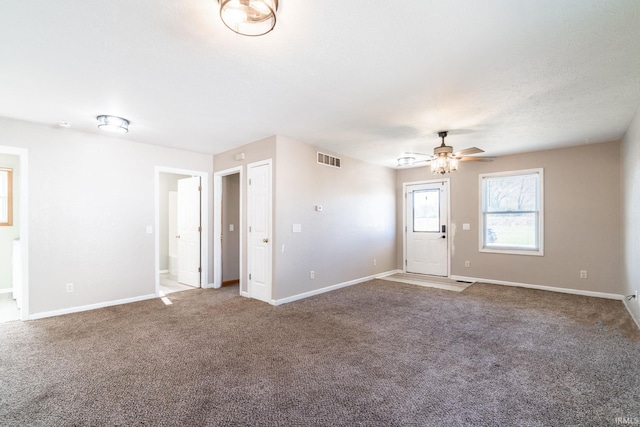 interior space with carpet flooring, visible vents, ceiling fan, and baseboards
