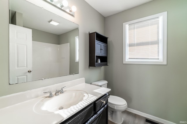 bathroom featuring vanity, toilet, visible vents, baseboards, and wood finished floors