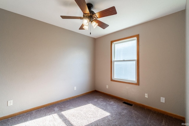 carpeted spare room featuring a ceiling fan, visible vents, and baseboards