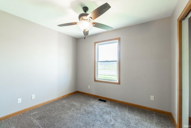 carpeted empty room featuring a ceiling fan, visible vents, and baseboards