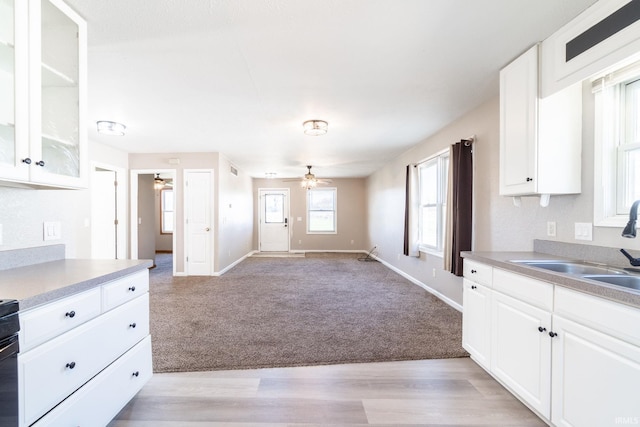 kitchen featuring baseboards, white cabinets, light carpet, and a ceiling fan