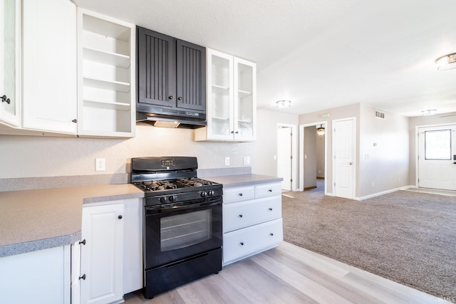 kitchen featuring under cabinet range hood, light countertops, white cabinets, black gas stove, and visible vents