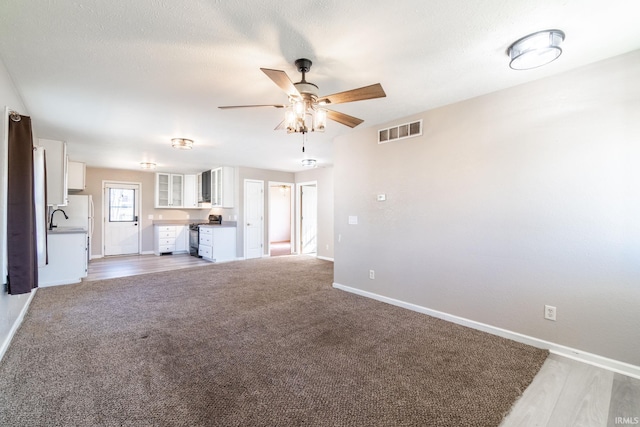 unfurnished living room featuring a sink, visible vents, ceiling fan, and baseboards