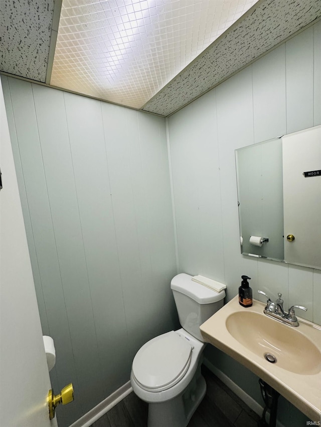 bathroom with toilet, a decorative wall, and a sink