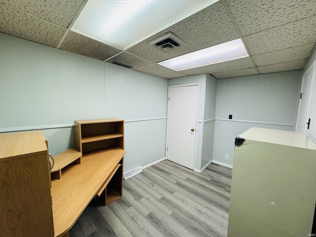 interior space with wood finished floors, a paneled ceiling, visible vents, and baseboards