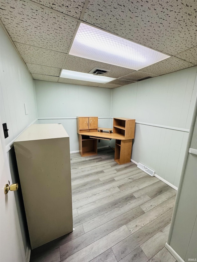 unfurnished office featuring visible vents, baseboards, a drop ceiling, and light wood-type flooring