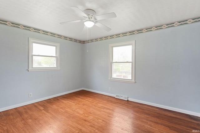 empty room featuring visible vents, light wood-style floors, and a healthy amount of sunlight