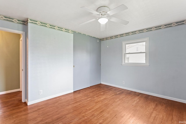 empty room featuring wood finished floors, ceiling fan, and baseboards