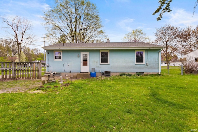 rear view of house featuring a lawn, a chimney, central AC unit, and fence