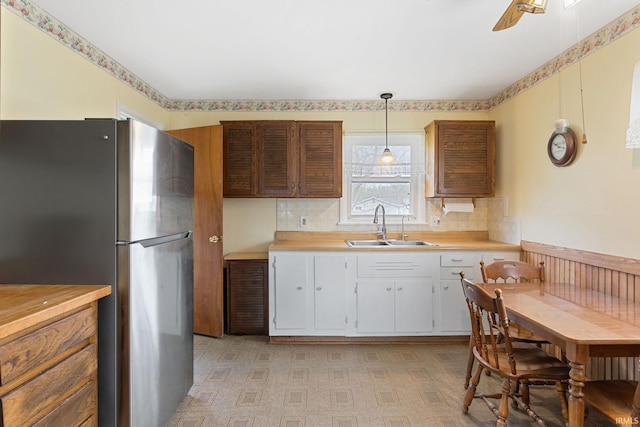 kitchen featuring white cabinetry, a sink, freestanding refrigerator, and light countertops