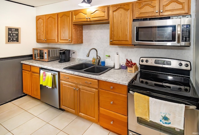 kitchen featuring light tile patterned floors, a sink, appliances with stainless steel finishes, and tasteful backsplash
