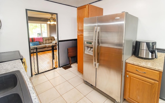 kitchen with stainless steel refrigerator with ice dispenser, ceiling fan, brown cabinets, and light tile patterned floors