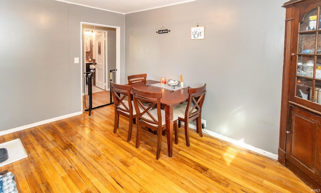 dining room featuring crown molding, light wood finished floors, and baseboards