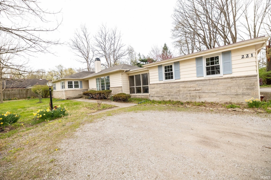 221 W Roselawn Dr, Logansport, IN 46947 - ranch-style home featuring a chimney, fence, a front lawn, and stone siding