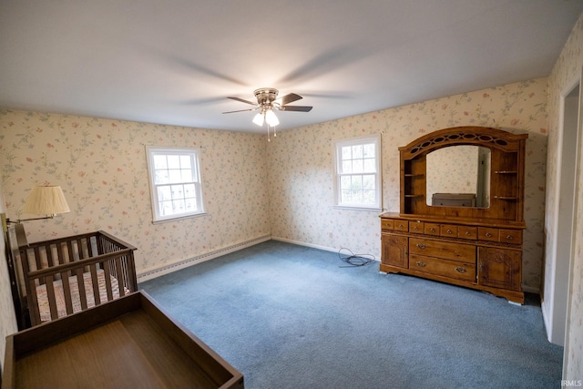 unfurnished bedroom featuring wallpapered walls, a ceiling fan, multiple windows, and carpet