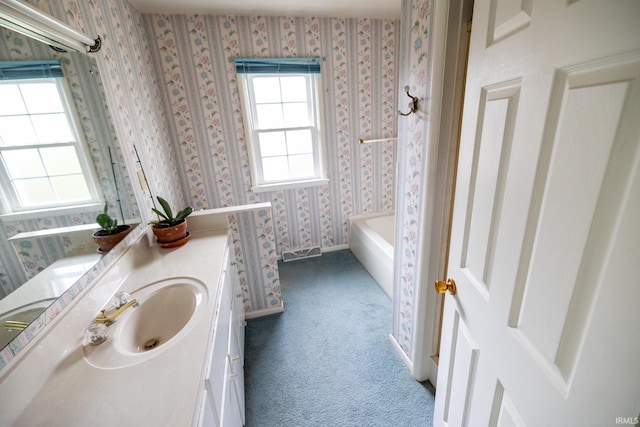 bathroom featuring a tub, wallpapered walls, and vanity