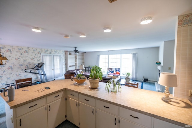 kitchen with open floor plan, ceiling fan, light countertops, and white cabinets