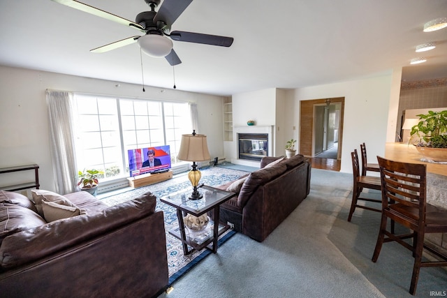 living room featuring ceiling fan, carpet, and a glass covered fireplace