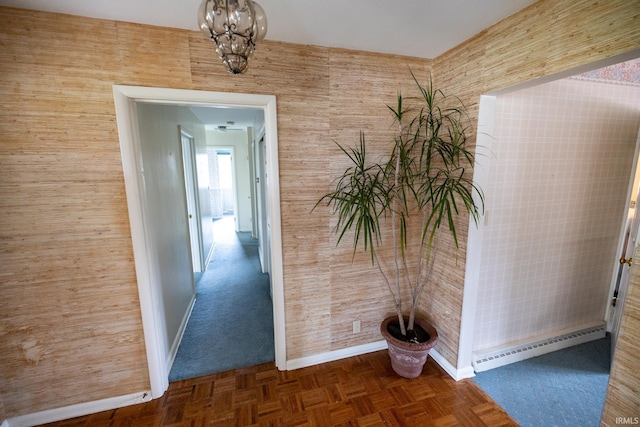 hall with a baseboard heating unit, a chandelier, and baseboards