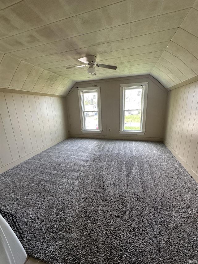bonus room featuring wooden walls, ceiling fan, lofted ceiling, and carpet floors