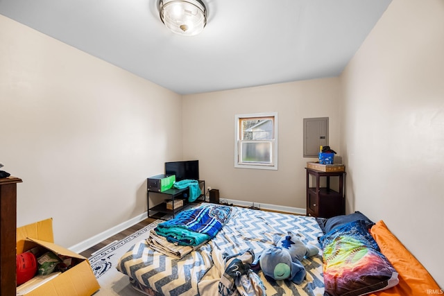 bedroom featuring wood finished floors, electric panel, and baseboards