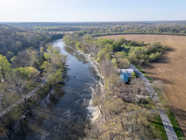 drone / aerial view featuring a wooded view, a rural view, and a water view