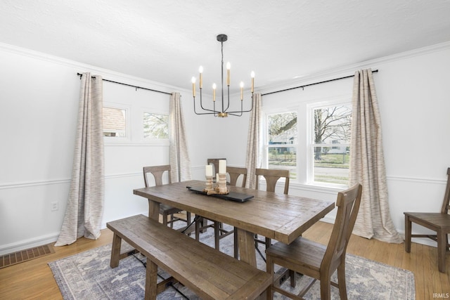 dining room featuring visible vents, ornamental molding, an inviting chandelier, and plenty of natural light
