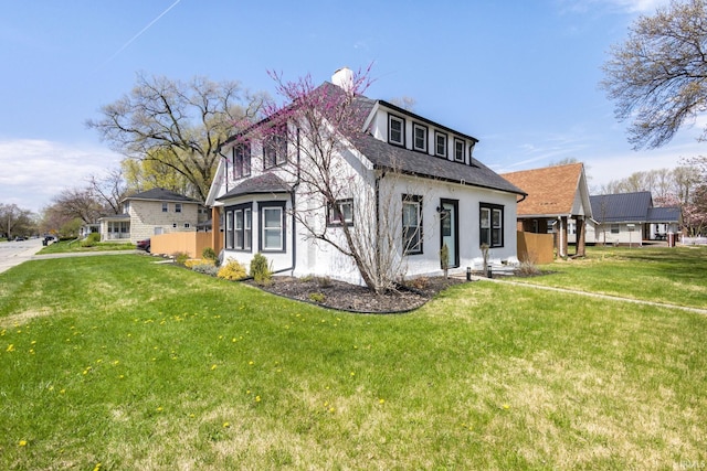 view of front of home featuring roof with shingles, a front lawn, and stucco siding
